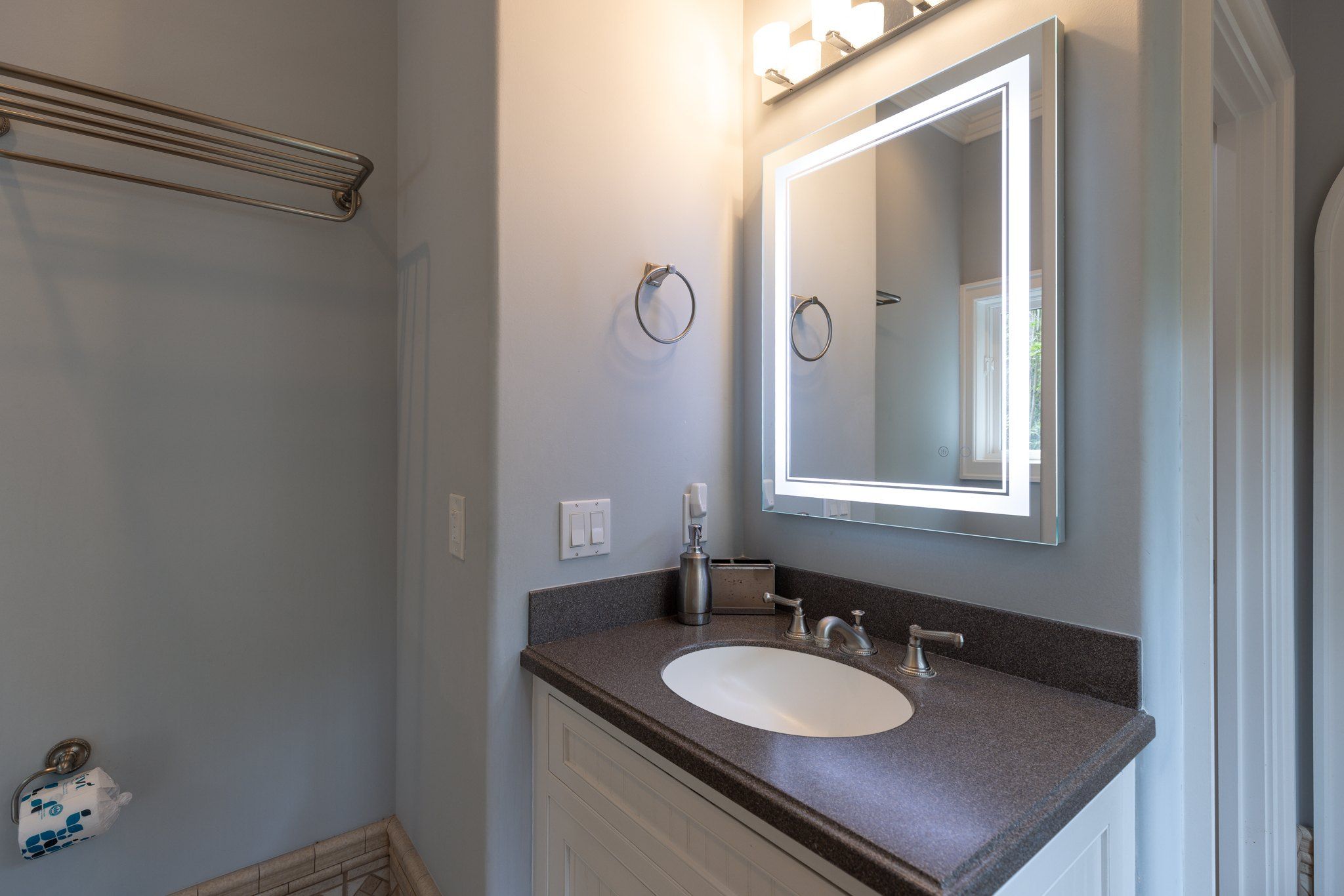 Guest bath with a dark stone vanity and framed mirror
