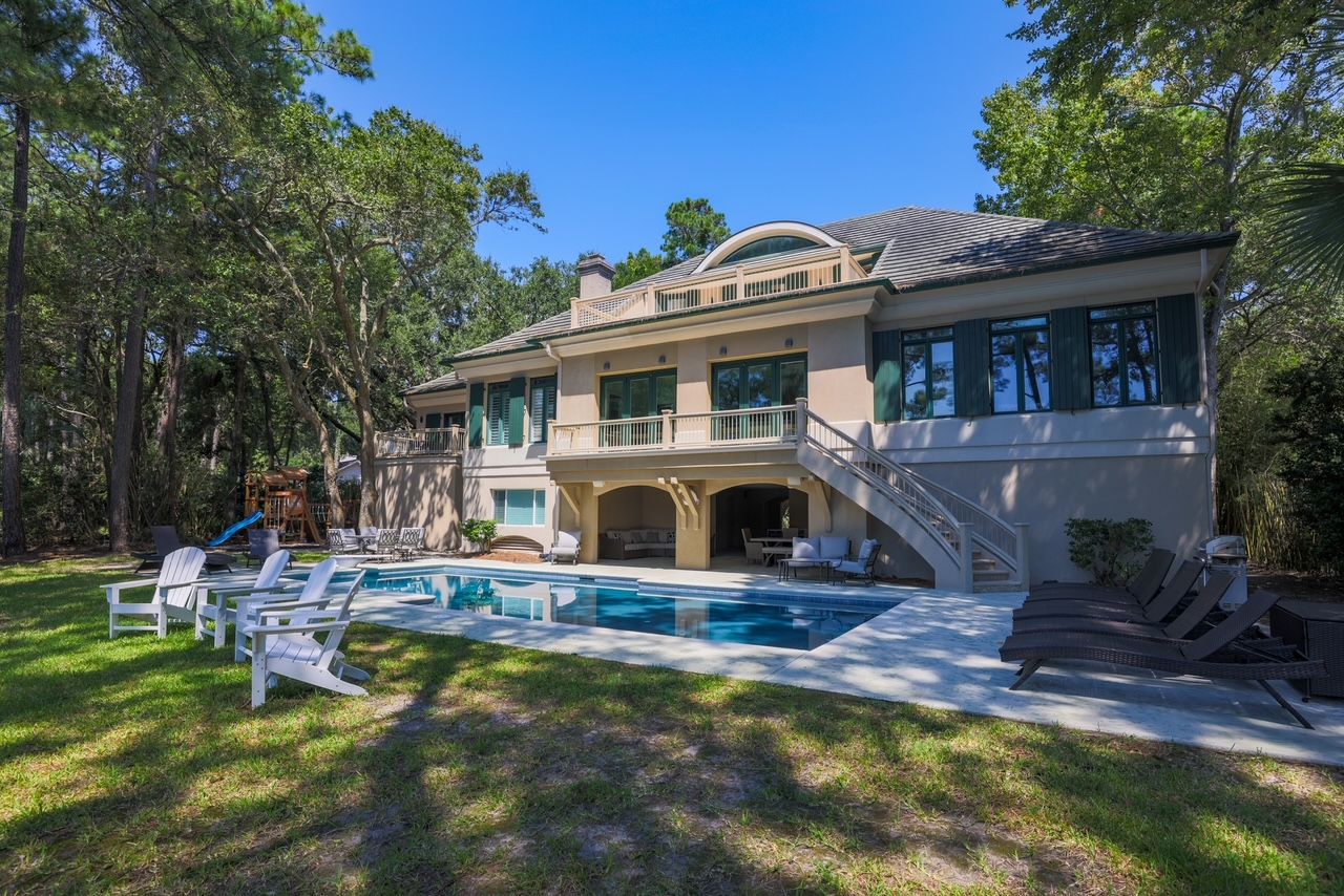 Rear lawn and pool of the estate framed by live oaks inside gated Palmetto Dunes