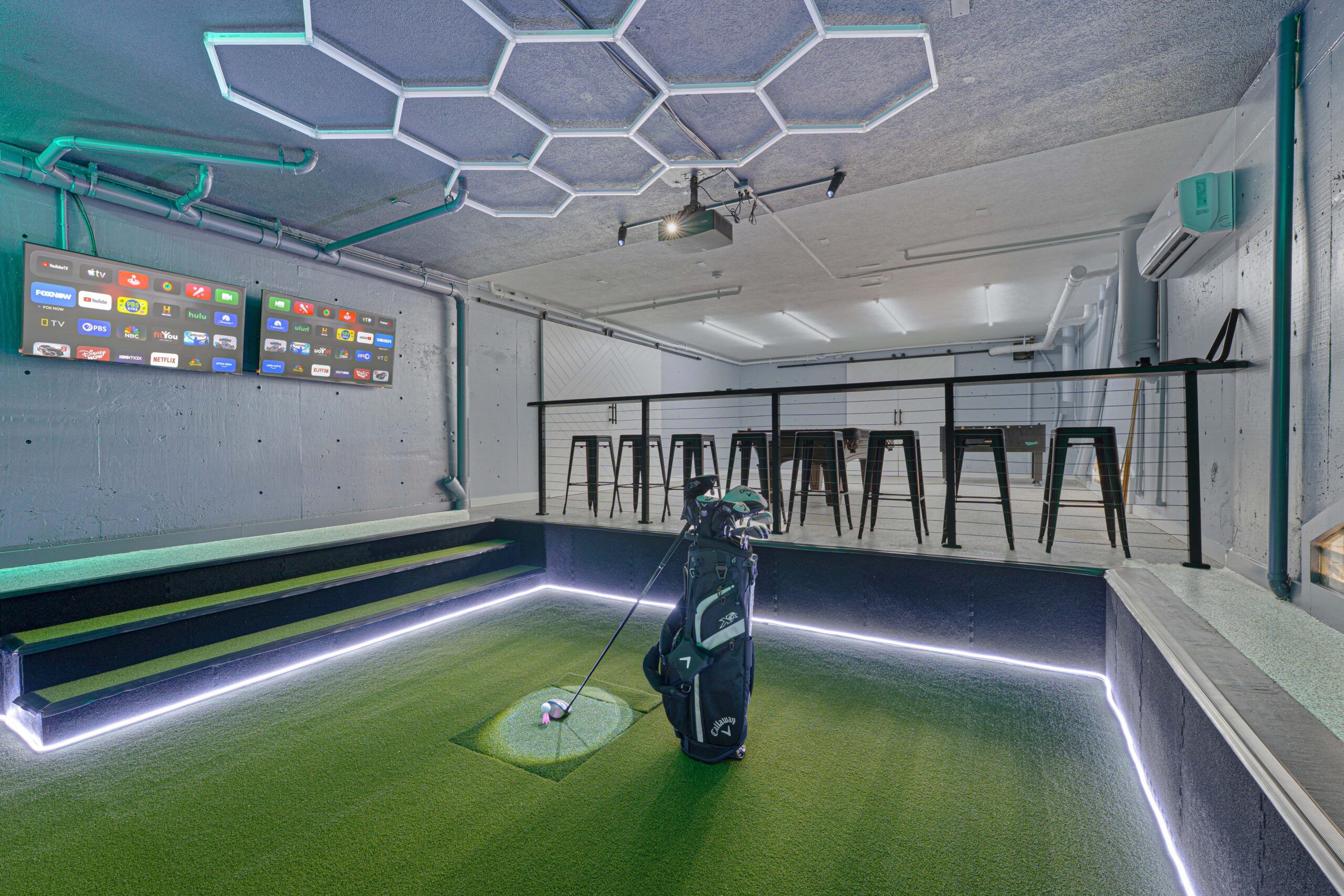 Bar-height seating and screens beside the in-home golf simulator at the estate