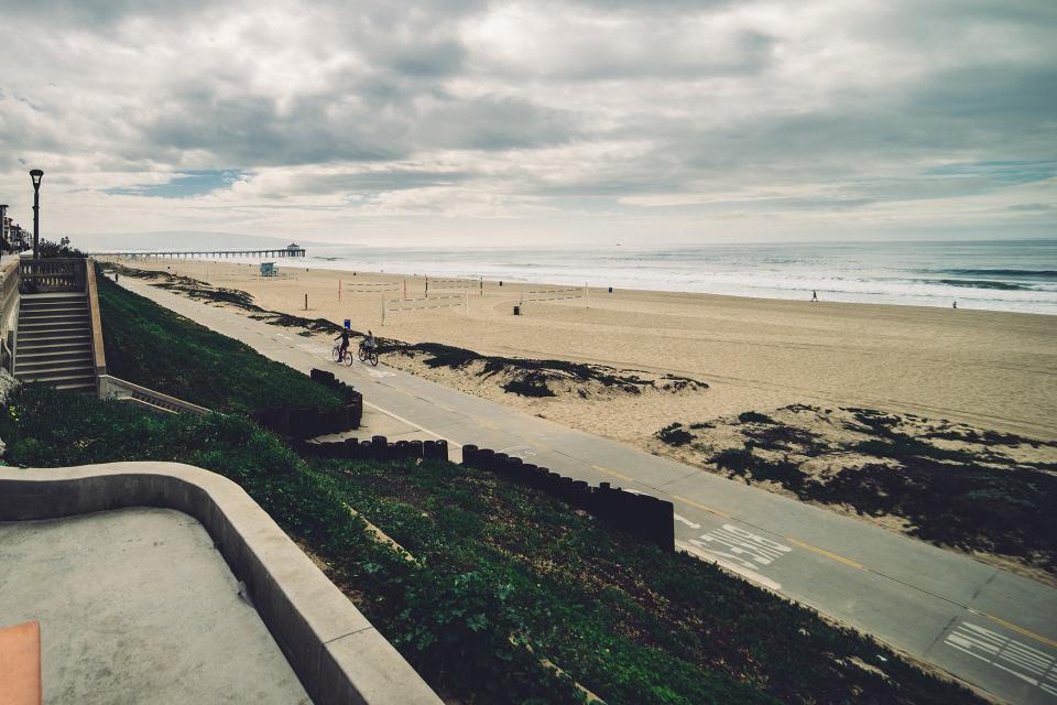 Bicycles resting on a wide sandy beach along the coast.